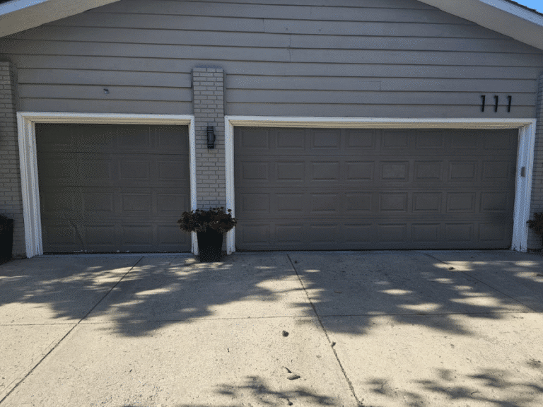 Gray single and double garage doors with raised panels.