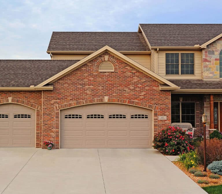Beige double garage door with raised panels and small upper windows.